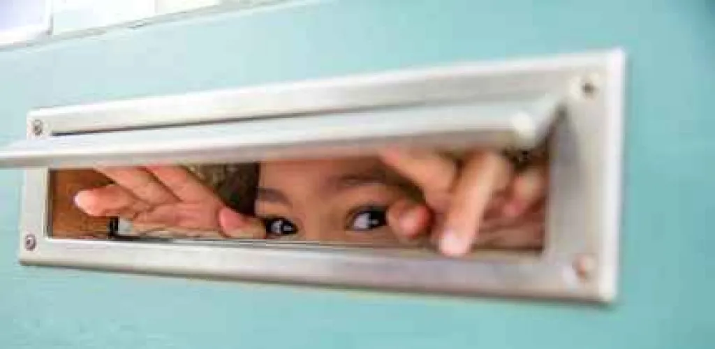 Enfant qui regarde par la boîte aux lettres