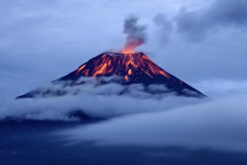 Eruption of tungurahua volcano at dusk with lava flows.
