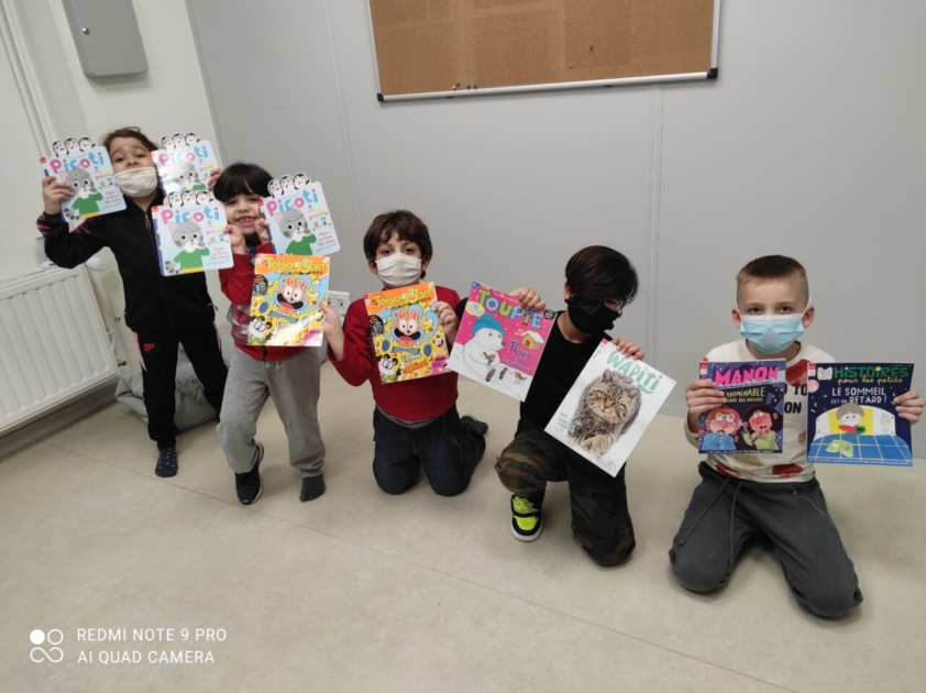 Enfants montrant des magazines offerts par Milan Presse à l'association Ma Chance Moi Aussi