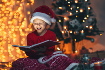 Enfant lisant devant sapin de Noël