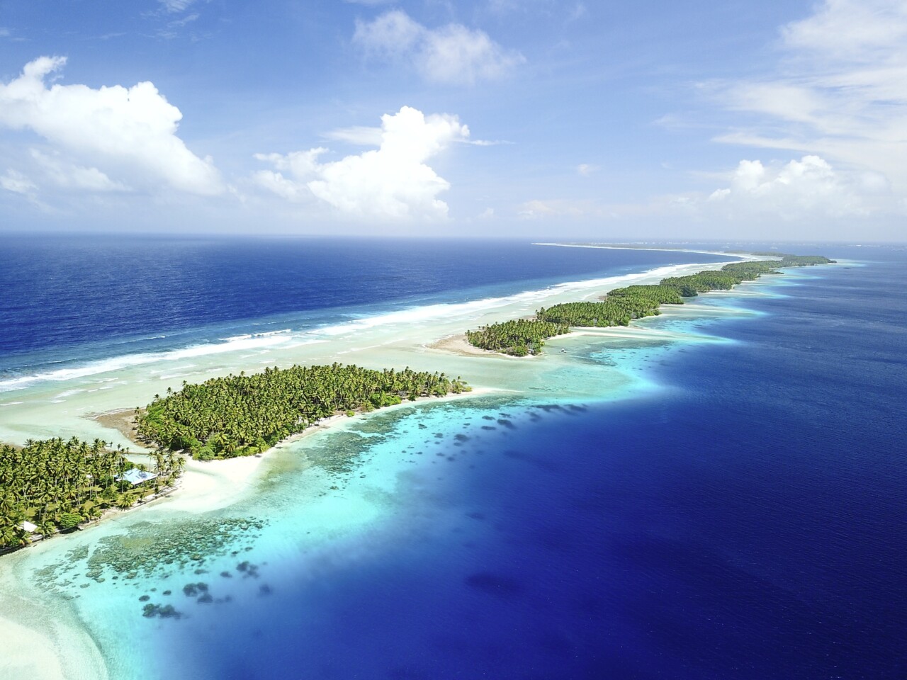 De petites îles qui se suivent sur une ligne jusqu'à se perdre à l'horizon. Elles sont peuplées de palmiers et bordées tout autour de plages aux eaux turquoises.
