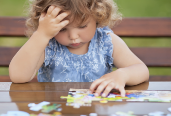 Petite fille qui se concentre pour faire une puzzle.