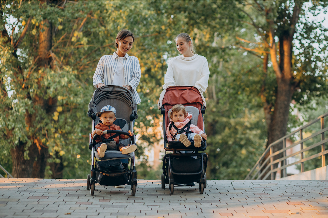 Deux amies promènent leur bébé en poussette.