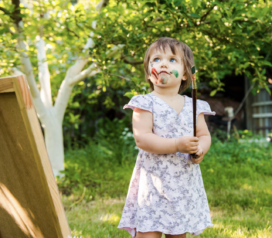 Petite fille qui s'amuse à peindre dans le jardin.