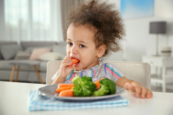 Enfant qui mange des légumes.