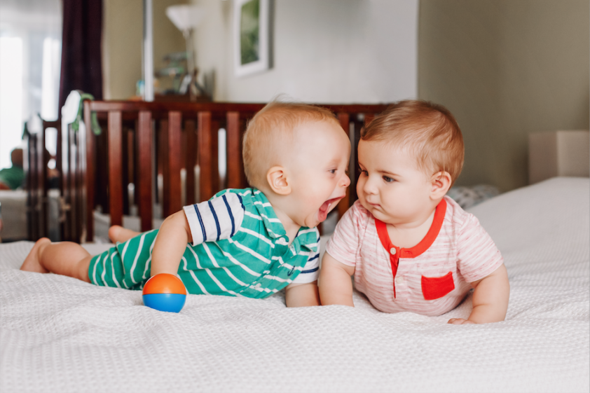 Deux bébés jouent, l’un s’approche pour mordre l’autre.